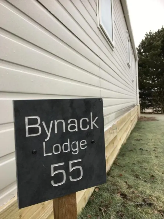 a sign in front of a house with a garage at Bynack Lodge in Boat of Garten