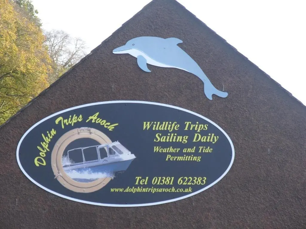 a sign with a dolphin and a boat on it at Black Isle Holiday Apartments in Avoch