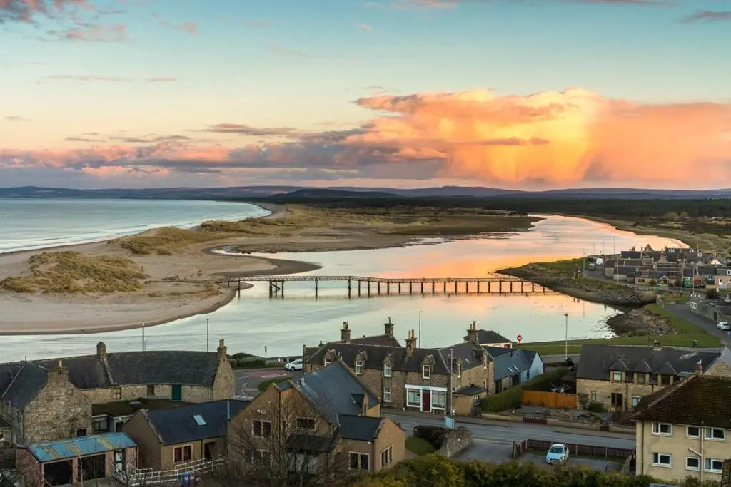 a view of a town with a pier and the ocean at Cosy Cottage Close to East Beach, Shops, Restaurants and RAF base in Lossiemouth