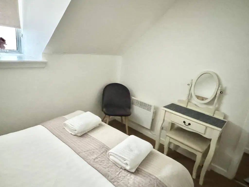 a bedroom with a bed and a mirror and a chair at City Centre House in Inverness