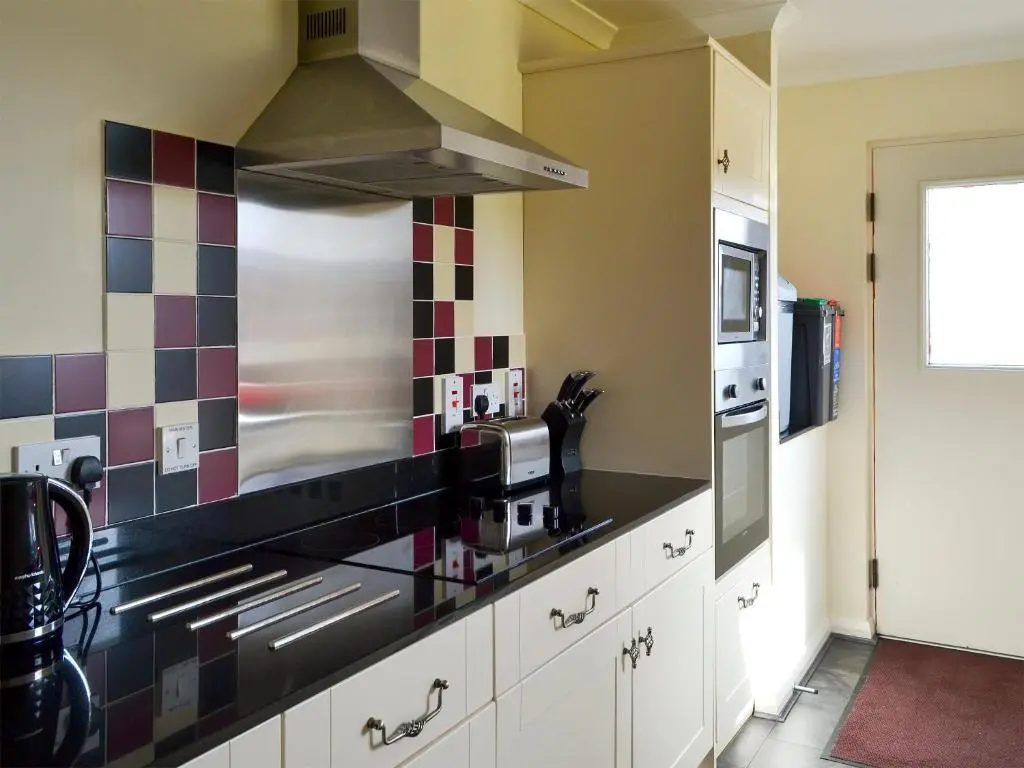 a kitchen with a stove top oven next to a microwave at Holly Lodge in Aviemore