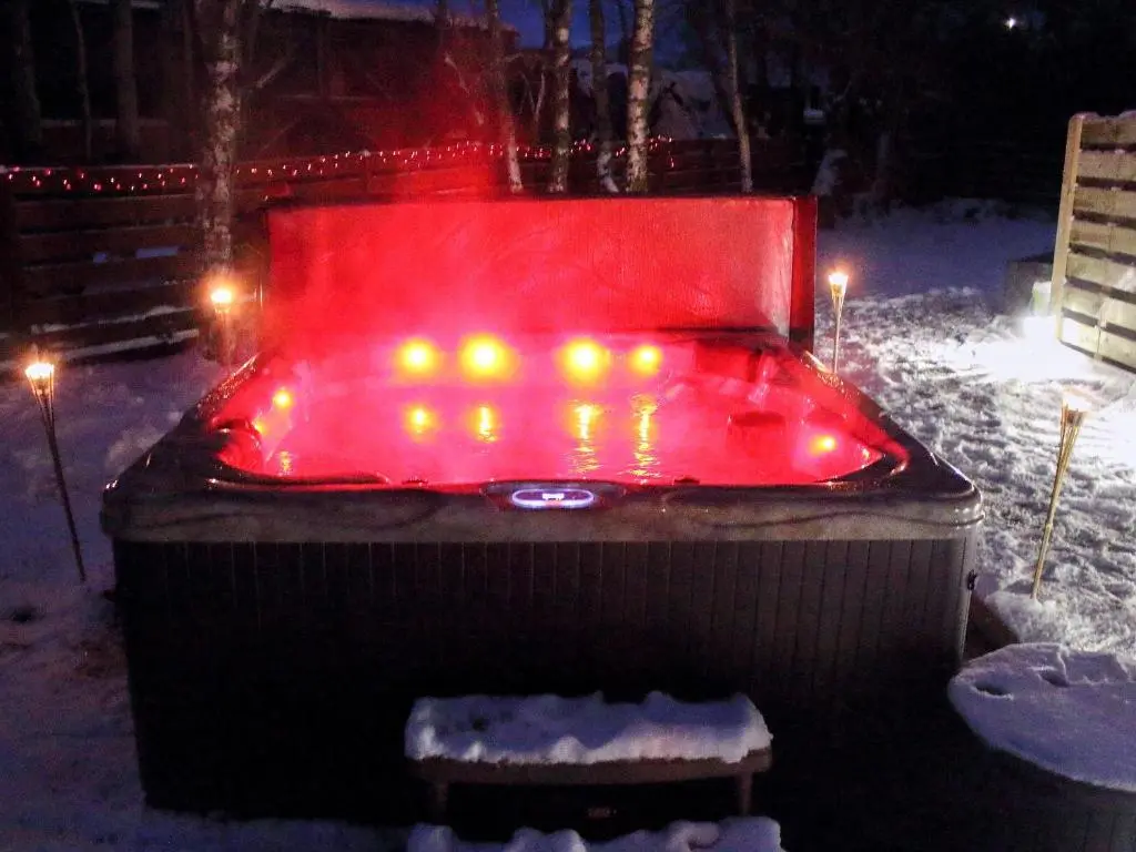 a hot tub with lights in the snow at night at Holly Lodge in Aviemore