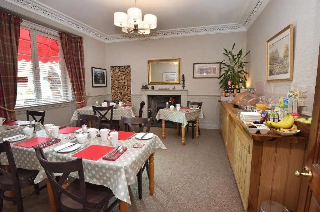 a dining room with tables and chairs and a fireplace at Acer Glen B&B in Inverness