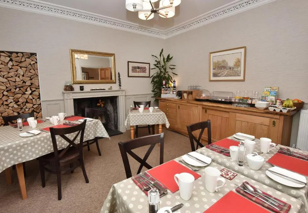 a dining room with two tables and a fireplace at Acer Glen B&B in Inverness