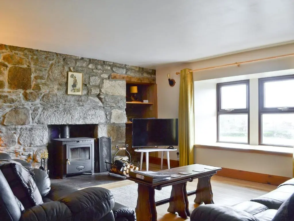 a living room with a couch and a stone fireplace at The Glebe in Duthil