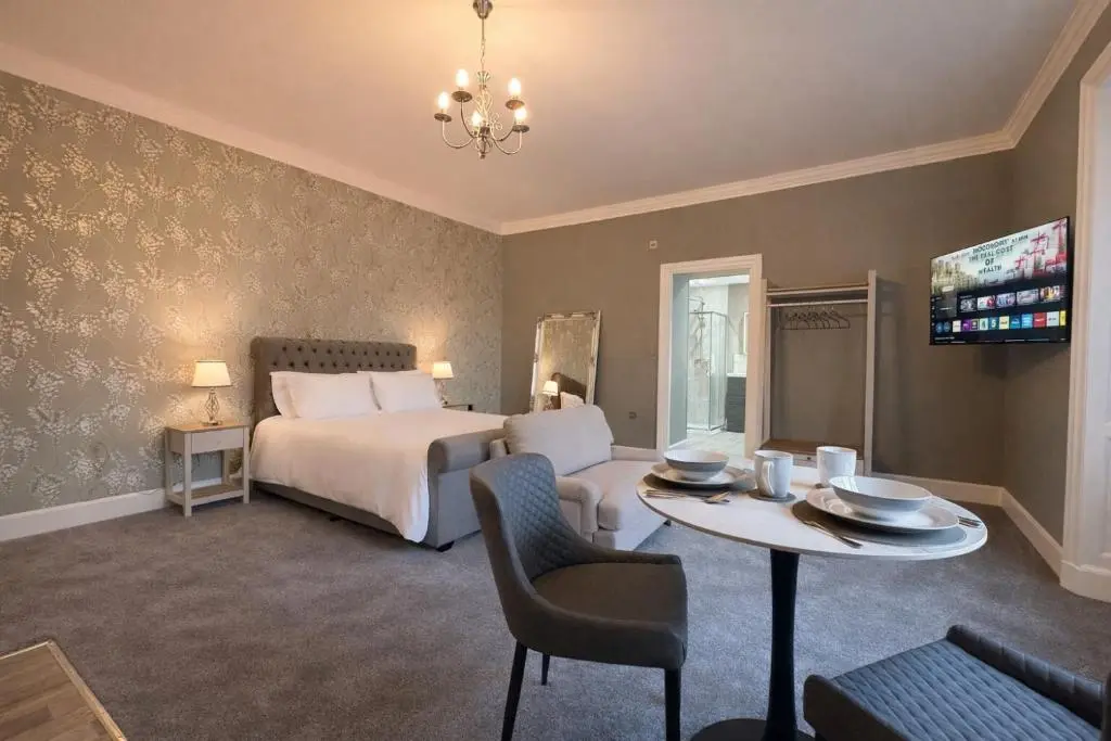 a hotel room with a bed and a table and a dining room at Rossal House Apartments in Inverness