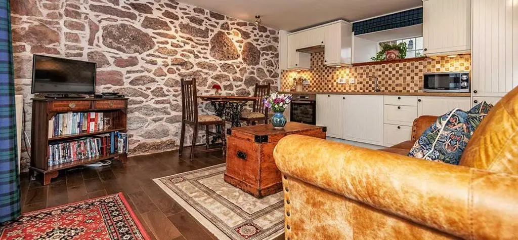 a living room with a couch and a stone wall at Mill Of Nethermill Holidays in Pennan