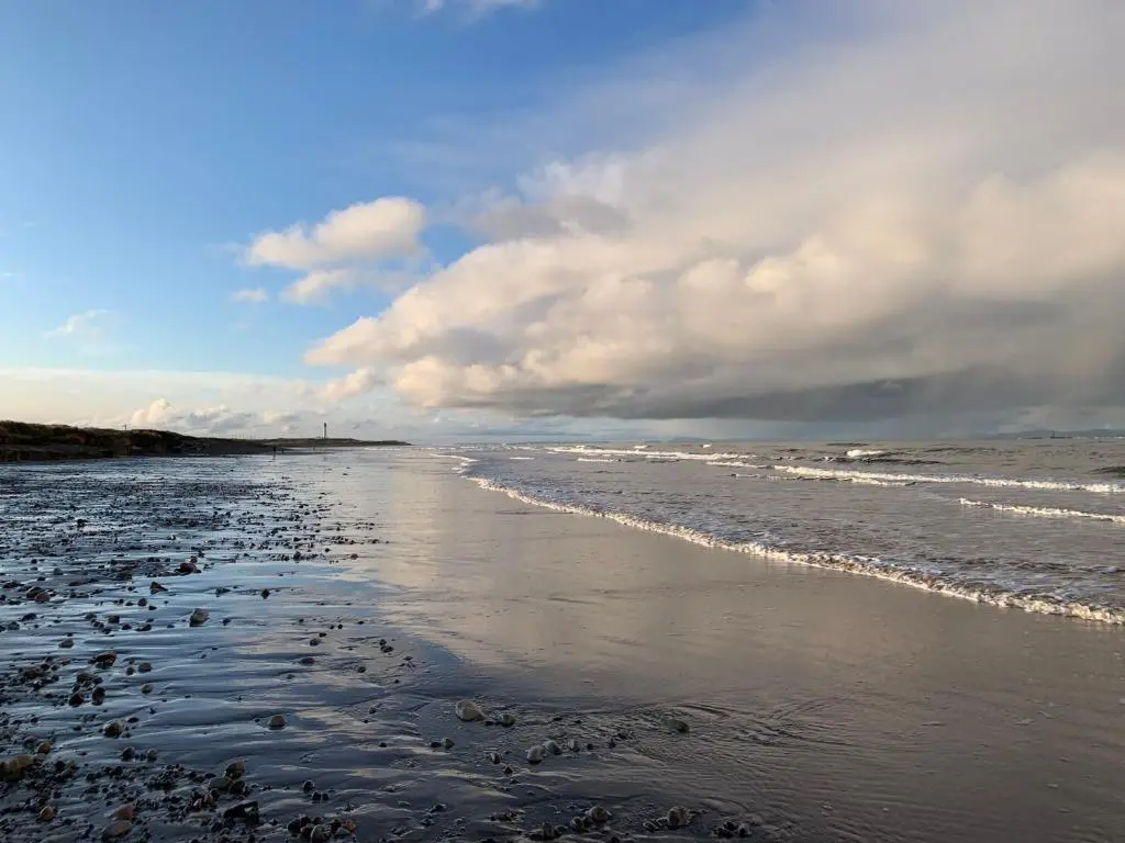 a beach with a cloudy sky and the ocean at Hayfield Apartment in Lossiemouth