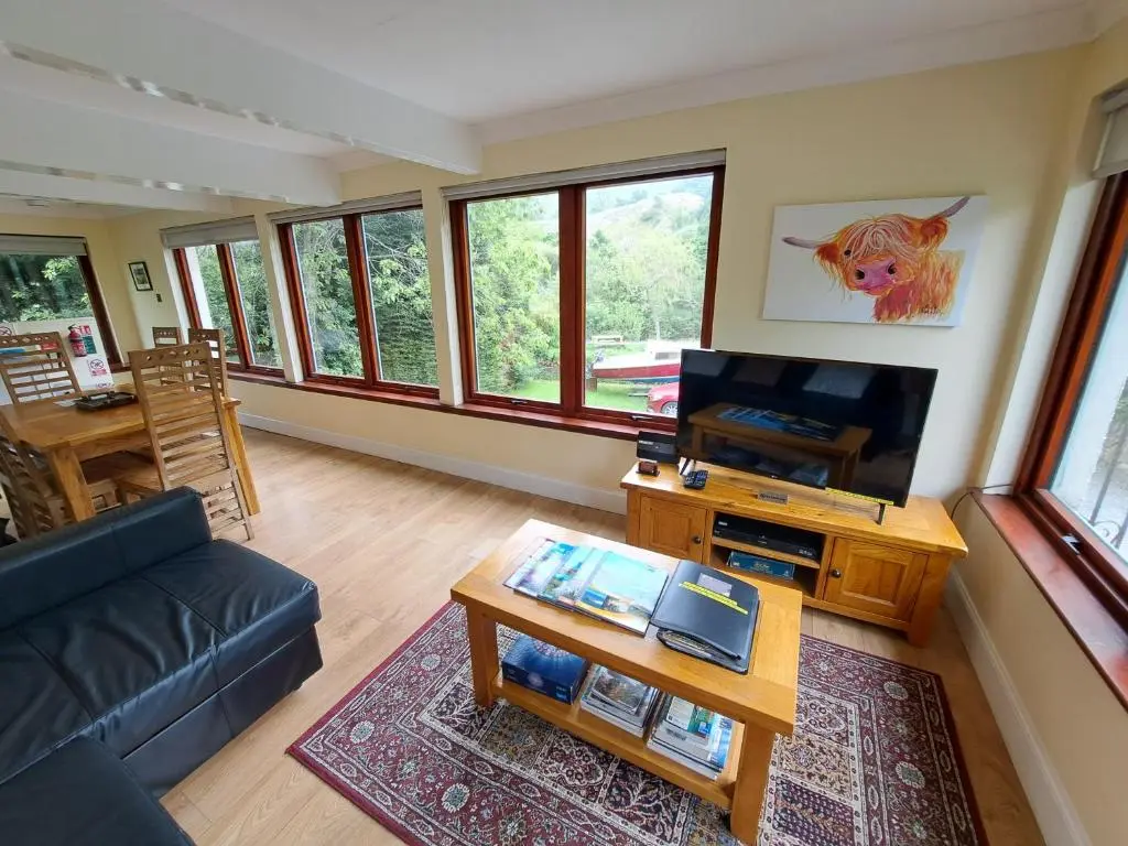 a living room with a couch and a tv at Loch Ness Balcony Apartment in Drumnadrochit