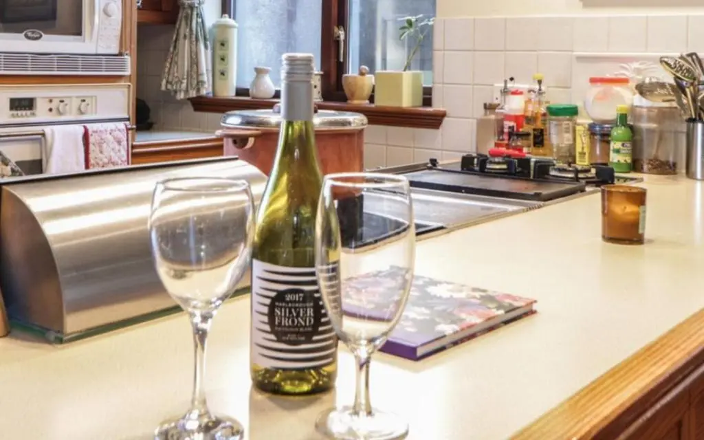 a bottle of wine and two glasses on a counter at Stunning 7 Bedroom Bungalow Alford Aberdeenshire in Alford