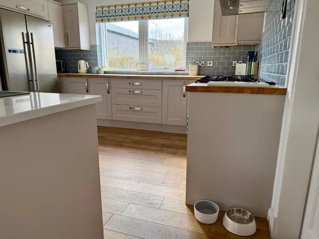 a kitchen with white cabinets and a tile floor at The Salmon Hut in Aberlour