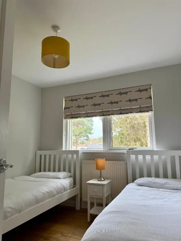 two twin beds in a bedroom with a window at The Salmon Hut in Aberlour