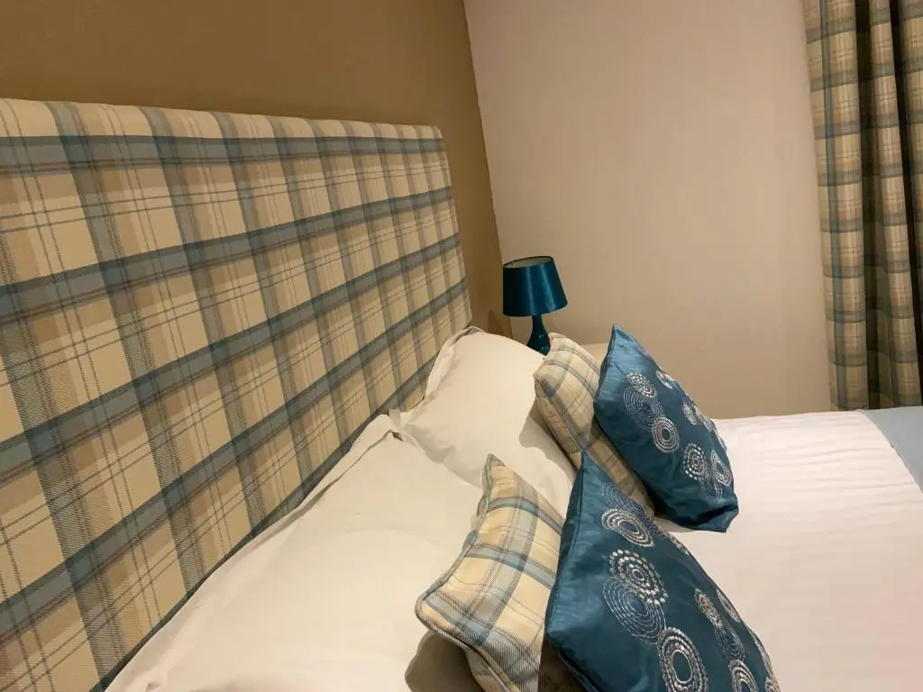 a bed with a head board with pillows and a lamp at One Bedroom Apartment Highland Club Scotland in Fort Augustus