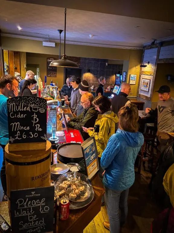 a group of people standing around a bar in a restaurant at The Balavoulin - Pub with Rooms in Aviemore