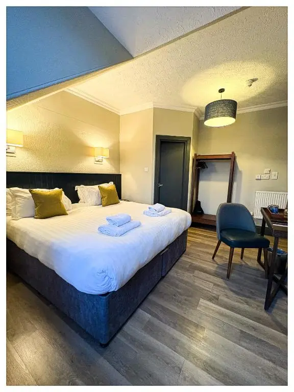a hotel room with a large bed and a chair at The Balavoulin - Pub with Rooms in Aviemore