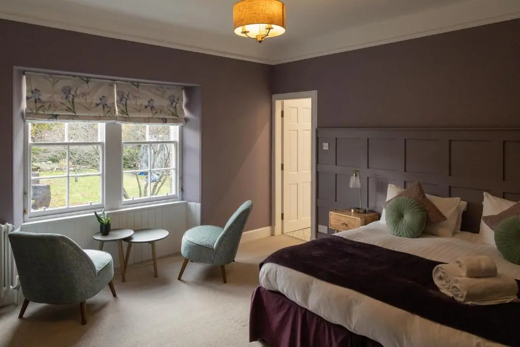 a bedroom with a large bed and a table and chairs at Craigellachie Lodge in Craigellachie