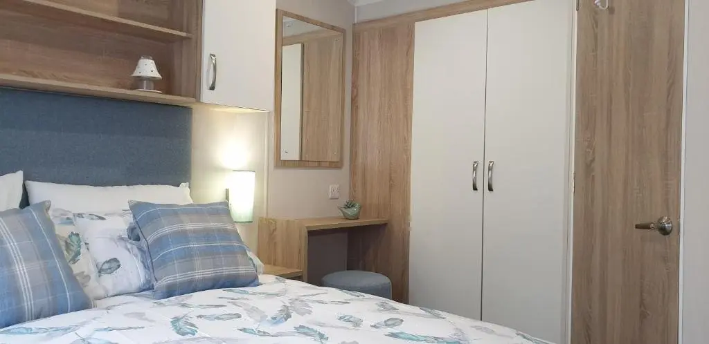 a bedroom with a bed with a blue headboard at Bonnie Gorm in Boat of Garten