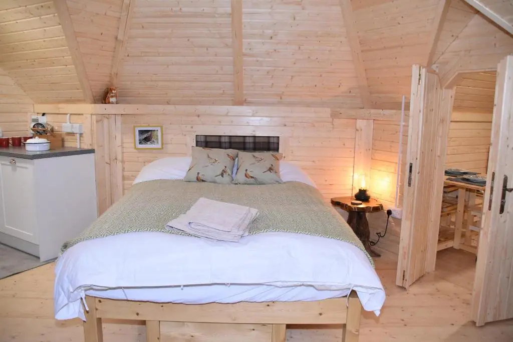 a bedroom with a bed in a wooden cabin at Cairngorm Bothies in Aboyne