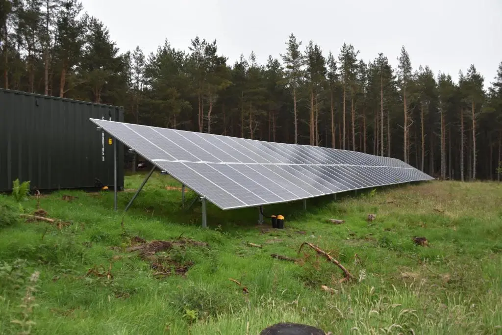 a solar array in a field with trees in the background at Cairngorm Bothies in Aboyne
