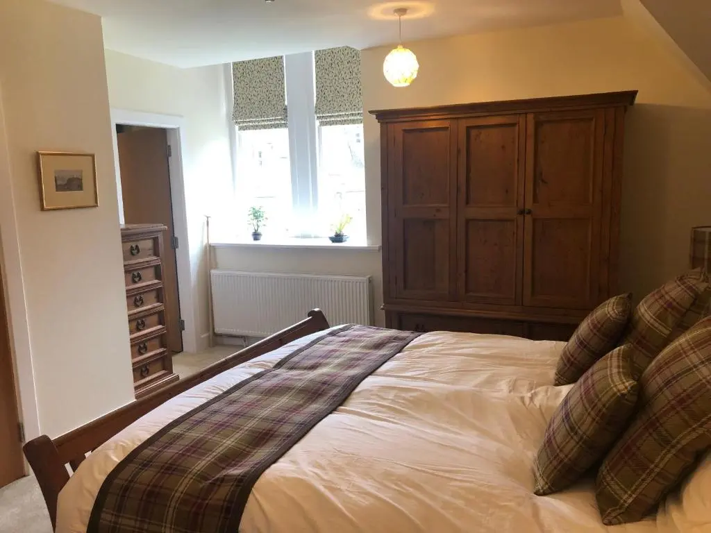 a bedroom with a bed with a dresser and a window at Loch Ness Moat House Apartments in Fort Augustus