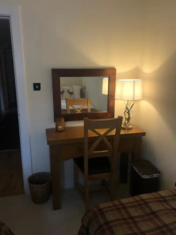a bedroom with a desk with a mirror and a chair at Loch Ness Moat House Apartments in Fort Augustus