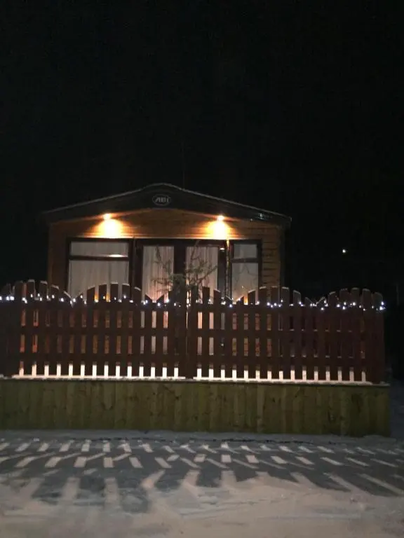 a wooden fence in front of a house at night at 81 The Heathers, Aviemore Holiday Park , Dalfaber rd Aviemore PH22 1PX in Aviemore