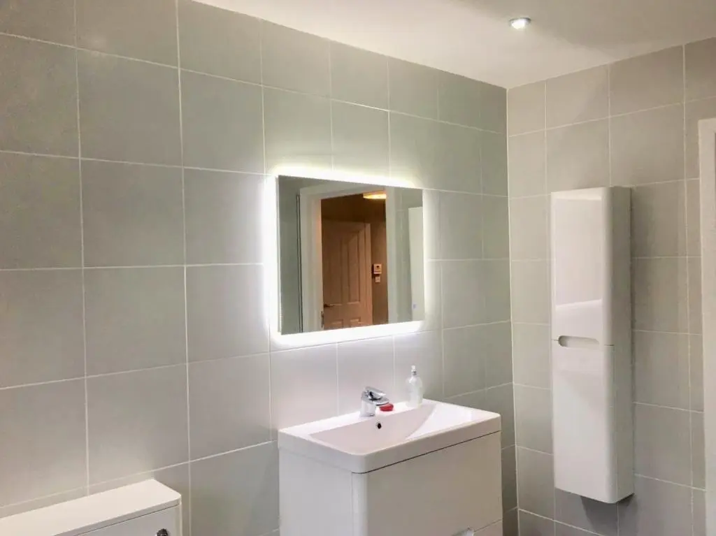 a bathroom with a white sink and a mirror at Culduthel Cottage in Inverness