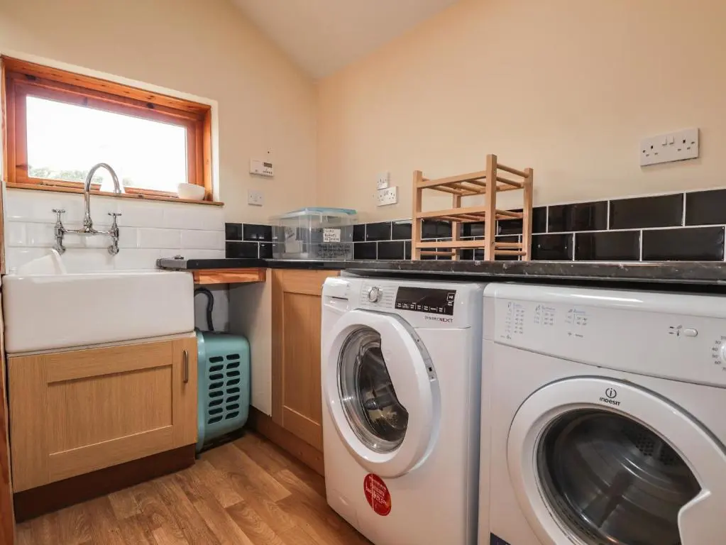 a kitchen with a washing machine and a sink at Glencanisp in Aviemore