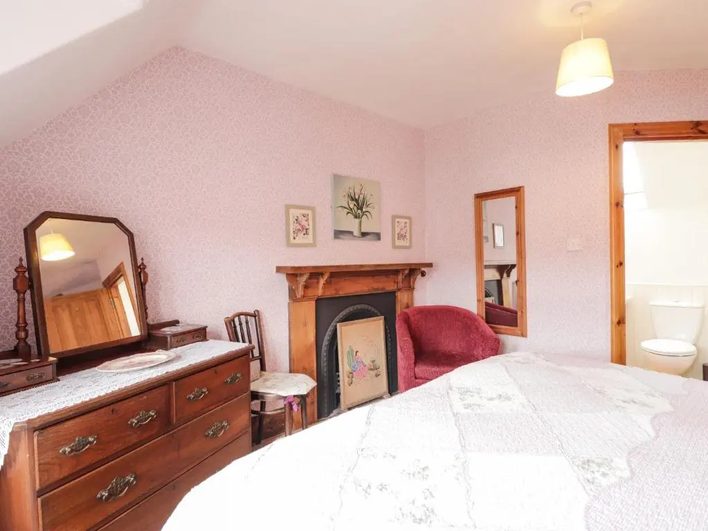 a bedroom with a bed and a mirror and a fireplace at Glencanisp in Aviemore