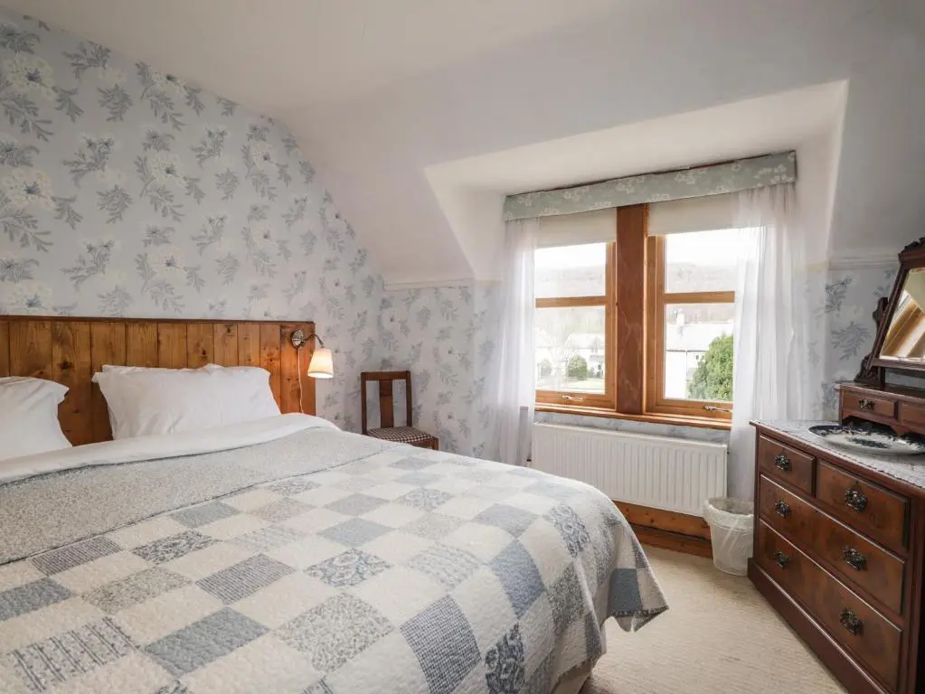a bedroom with a large bed and a window at Glencanisp in Aviemore