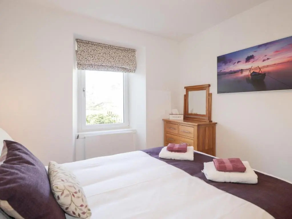 a bedroom with a large white bed and a window at Faodail Glenlia in Foyers