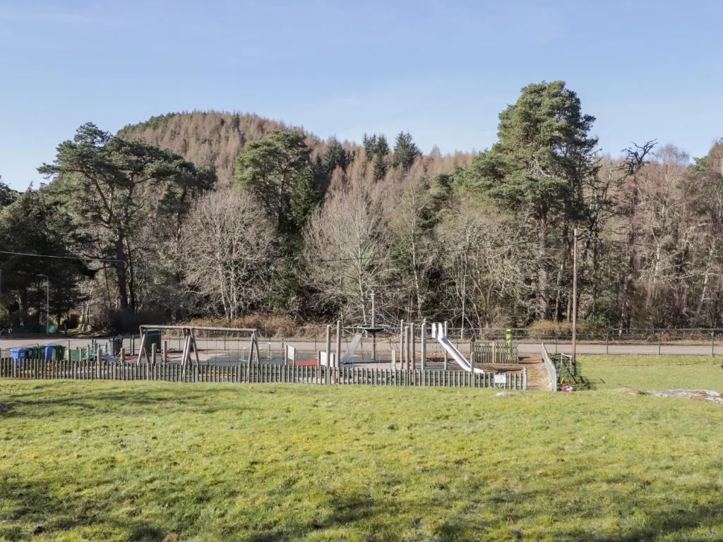 a playground in a park with a hill in the background at Faodail Glenlia in Foyers