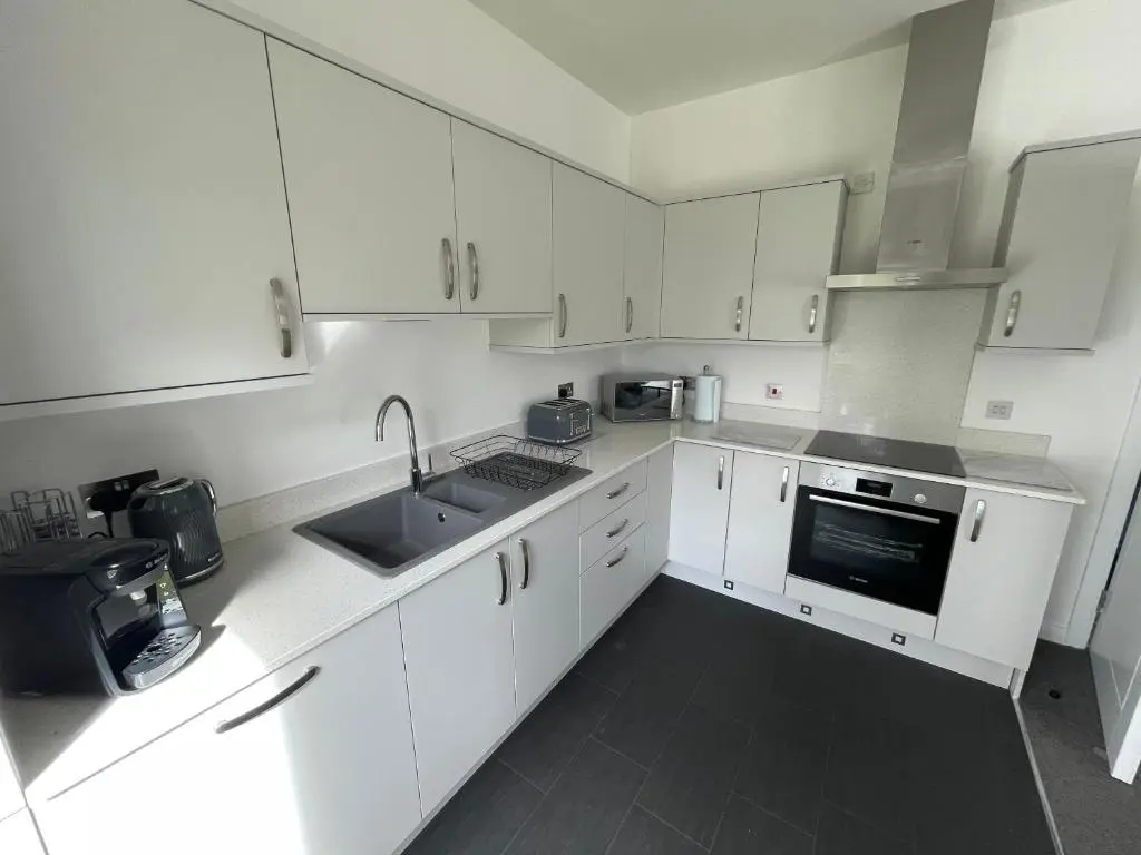 a white kitchen with white cabinets and a sink at Atholl Place View in Inverness
