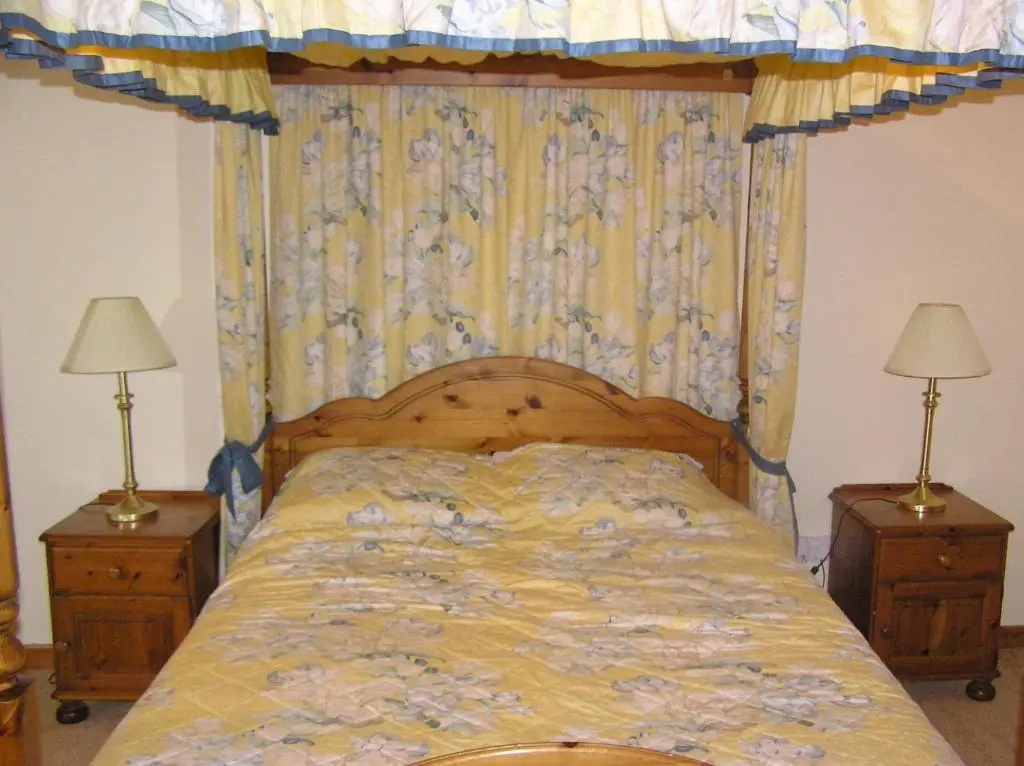 a bedroom with a bed with a canopy and two lamps at The Antlers in Lybster