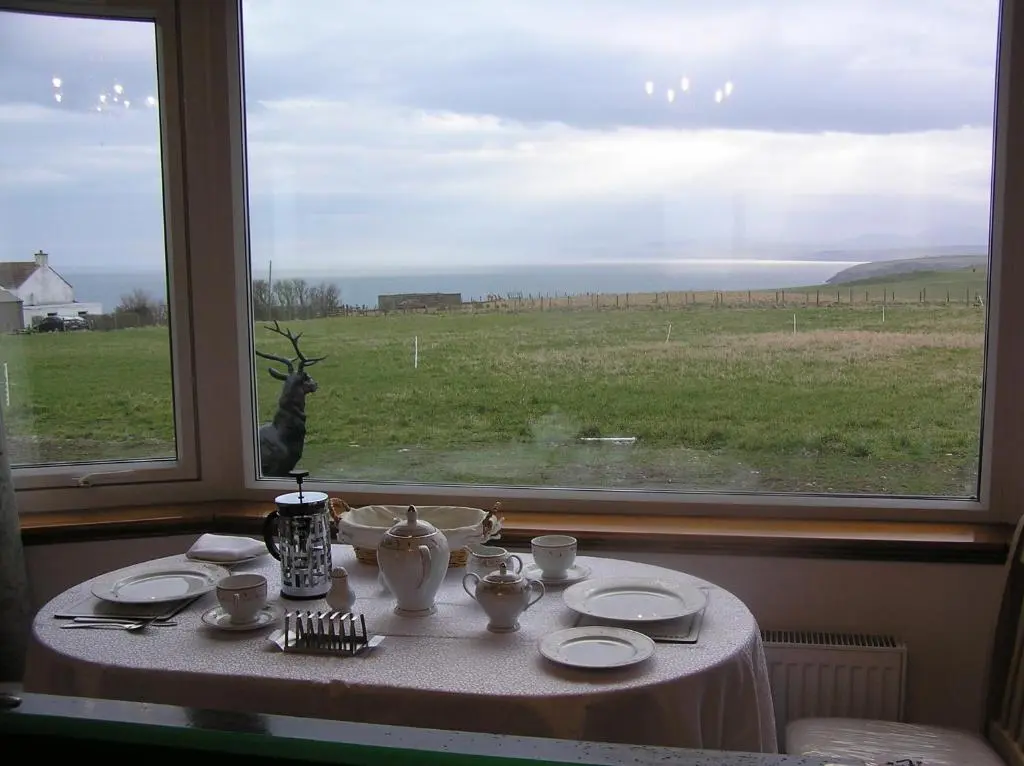 a table with a view of a field from a window at The Antlers in Lybster
