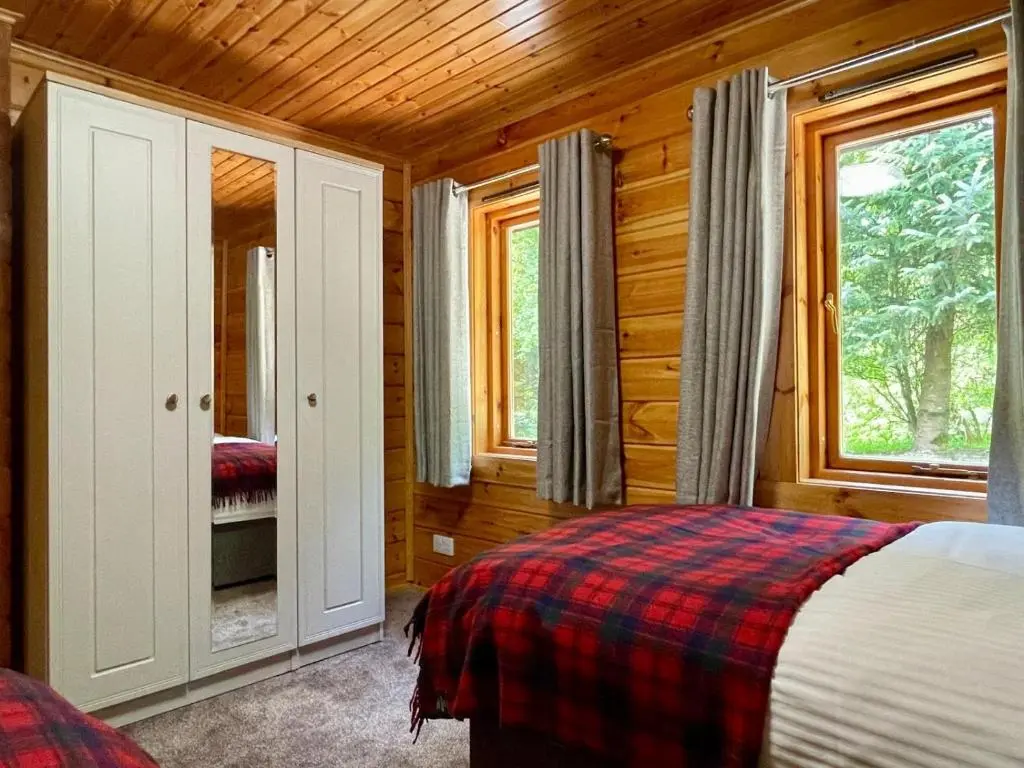 a bedroom with a bed in a log cabin at Deveron Valley Cottages in Marnoch