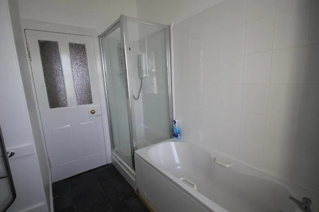 a white bathroom with a shower and a bath tub at Covesea Lighthouse Cottages in Lossiemouth