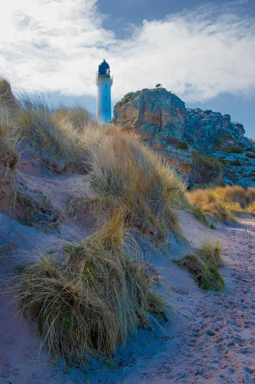 a lighthouse sitting on top of a hill with tall grass at Covesea Lighthouse Cottages in Lossiemouth