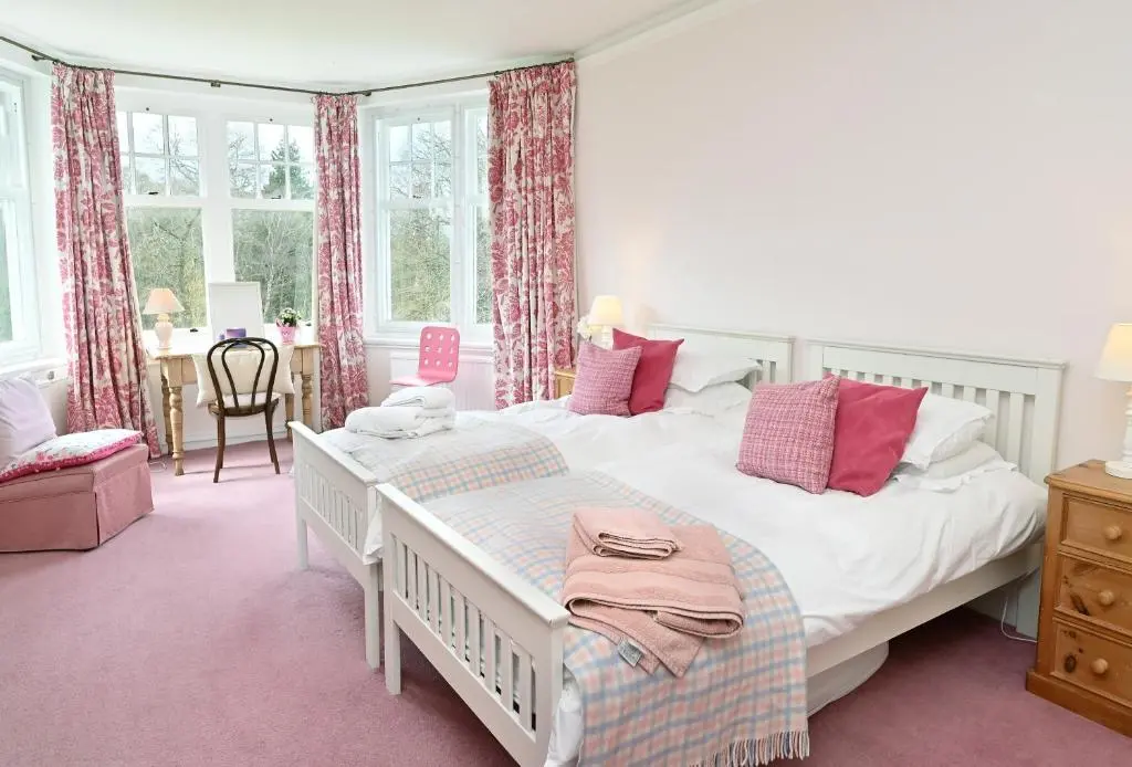 a bedroom with a bed and a desk and windows at Willowvale in Nairn