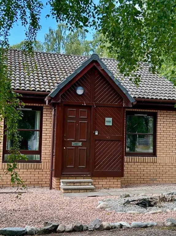 a small house with a brown door and windows at Rendezvous , Aviemore in Aviemore