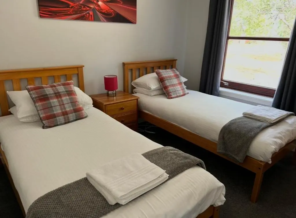 a bedroom with two beds and a window with at Rendezvous , Aviemore in Aviemore