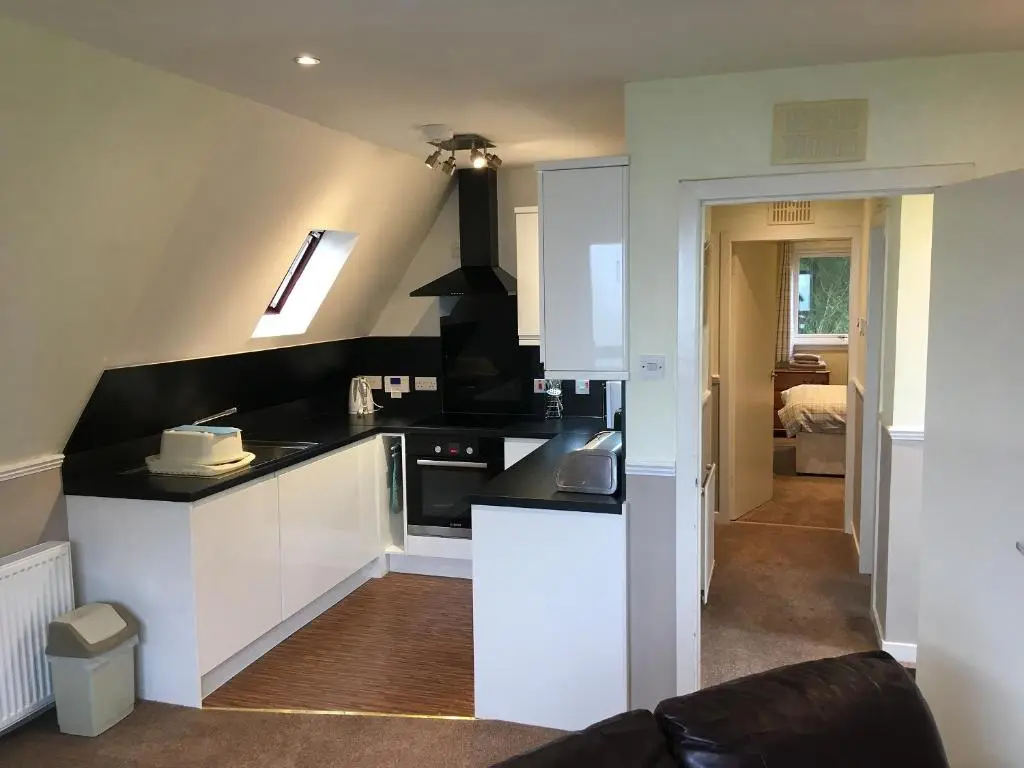 a kitchen with white cabinets and black counter tops at Thistle Lodge - Uk7051 in Glenurguhart