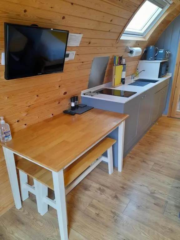 a kitchen with a table and a tv on a wall at North Star Glamping in Lybster