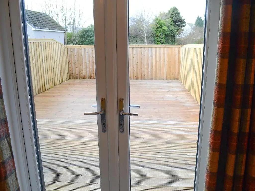 an open door to a patio with a wooden deck at Mile End Cottage in Inverness