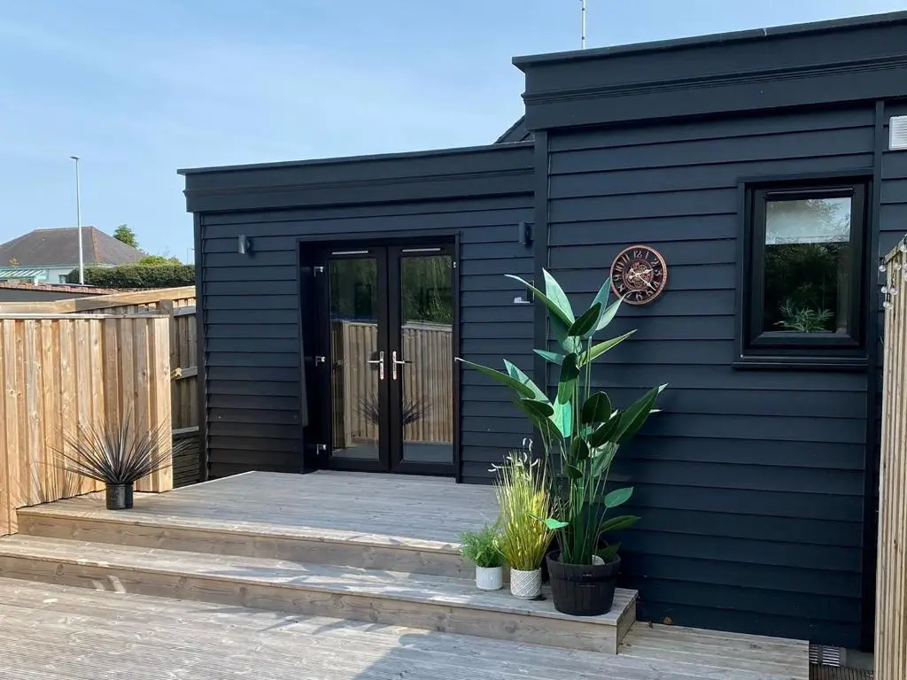 a black house with a black door and some plants at Mile End Cottage in Inverness