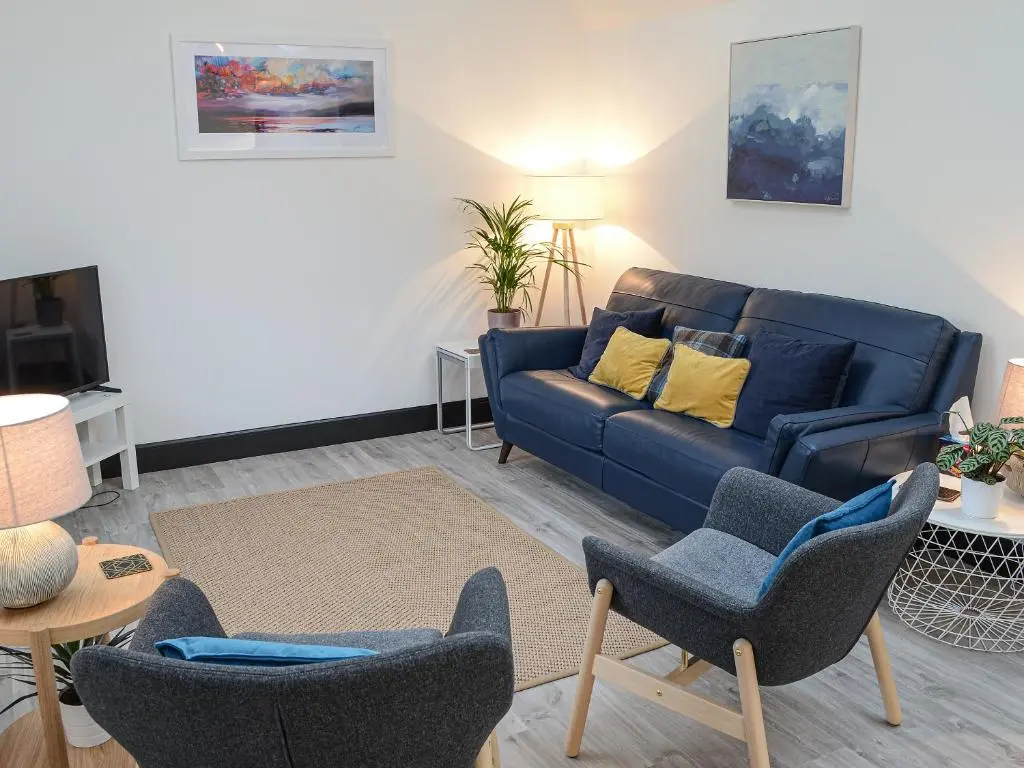 a living room with a blue couch and chairs at Mile End Cottage in Inverness