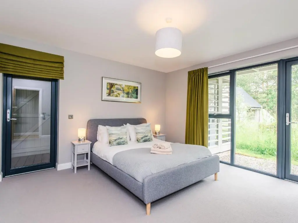 a bedroom with a bed and sliding glass doors at Golden Eagle Lodge in Kingussie