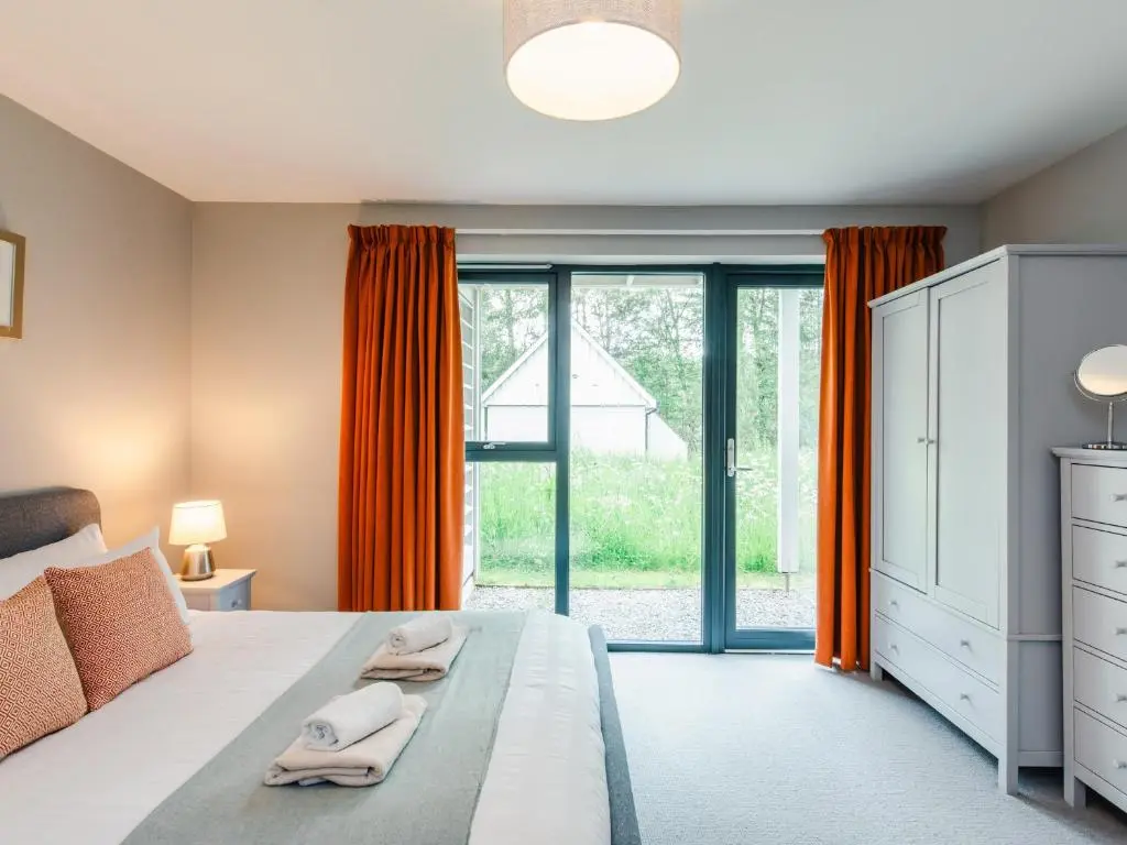 a bedroom with a bed and a large window at Red Deer Lodge in Kingussie