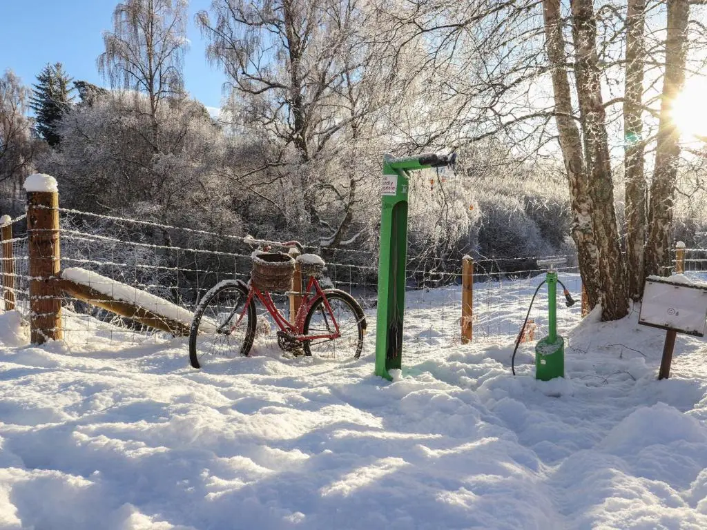 a bike parked next to a fence in the snow at Red Deer Lodge in Kingussie