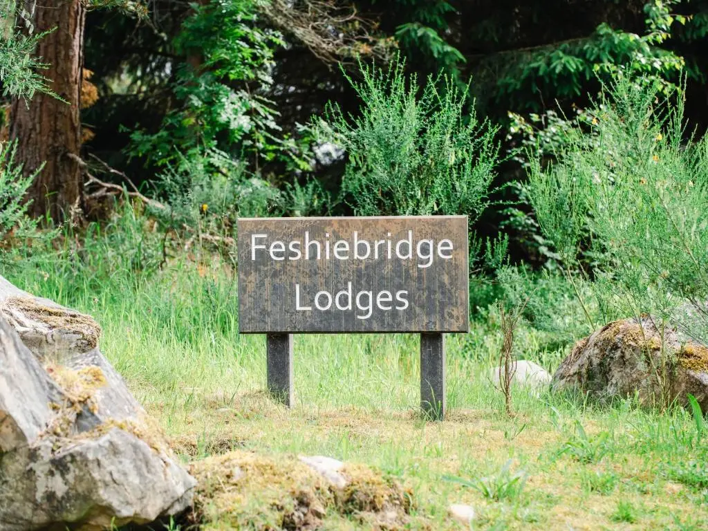 a sign in the grass next to some rocks at Mountain Hare Apartment in Kingussie
